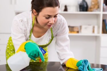 Mujer limpiando muebles de madera de la cocina