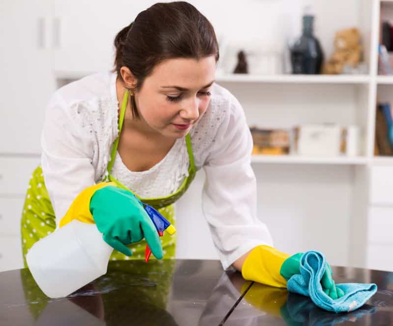 Mujer limpiando muebles de madera de la cocina